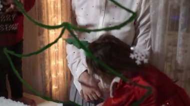 Otantik sevimli bir anne ve iki küçük anaokulu öğrencisi kız ve erkek kardeş 2-4 yaşlarında pencereye Noel ağacı çiziyor. Çocuklu genç bir kadın kar taneleri yapıştırıyor. Xmas, yeni yıl, kış konsepti.