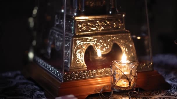 Θρησκεία, διακοπές, έννοια - Panning along rays of light from window in smoky dusty room falling on salt throne in Christian Orthodox temple with burning candle lamp nearby menorah κάτω από πολυέλαιο. — Αρχείο Βίντεο