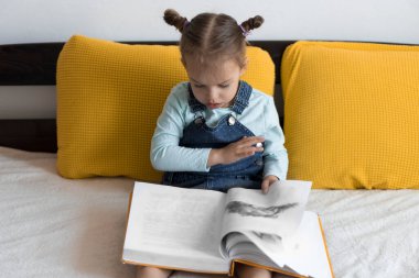 İki küçük çocuk sarı yatakta büyük, ilginç peri masalları kitabı okuyor. Kardeş ikizler evde karantinada eğleniyor, mutlu çocuk. Arkadaşlık, aile, eğitim kavramı