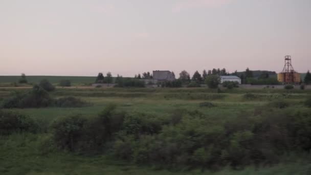 美しい自然の野生のフィールドや森林鉄道のトラックの風景の中に窓の高速列車からの眺め夏の背景に夕日のレール。交通、旅行、鉄道、通信の概念 — ストック動画