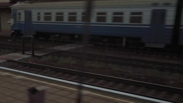 Widok z okna pociąg dużych prędkości na starej opuszczonej stacji i zardzewiałych wagonów towarowych tory kolejowe na wieczornym zachodzie słońca niebo w tle lata. Transport, podróże, kolej, koncepcja komunikacji — Wideo stockowe