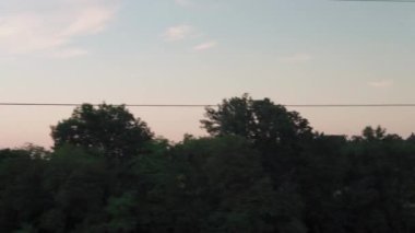 Yüksek hızlı trenden manzarası olan doğa yolu manzarası akşam gökyüzünde arabasıyla yaz arkaplanında gün batımı. Kırmızı batan güneş ufukta. Ulaşım, seyahat, demiryolu, iletişim konsepti