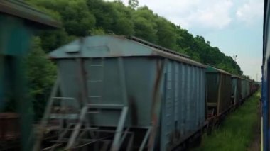 Terk edilmiş eski istasyon ve paslı yük vagonlarının penceresinden manzarası güneşli yaz günlerinde tren rayları. Ulaşım, seyahat, demiryolu, iletişim konsepti