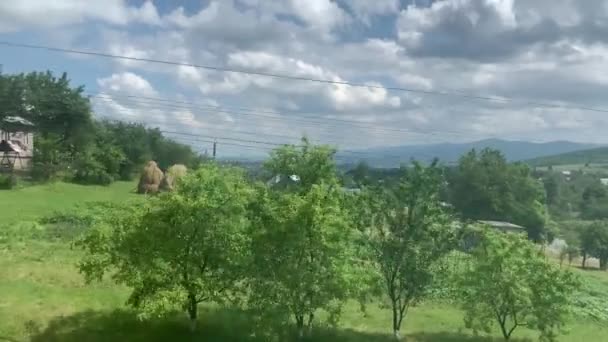 Wazig zijaanzicht van hogesnelheidstrein op landschap van prachtige natuur wild veld en bergen bos op schone zonnige dag in de zomer achtergrond. Vervoers-, reis-, spoorweg- en communicatieconcept — Stockvideo