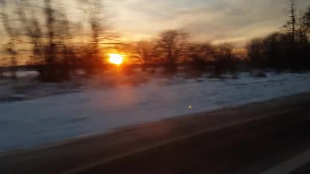 pohled z okna vysokorychlostního vlaku na krajinu krásné přírody divoké zasněžené mrazivé studené pole a holé stromy les slunečný večer západ slunce v zimě pozadí. Doprava, cestování, železniční koncept