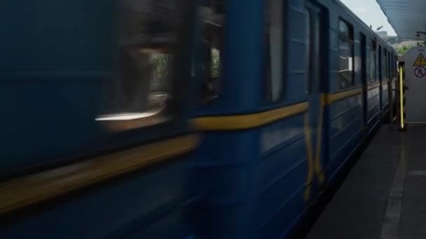 Il treno blu giallo della metropolitana passa attraverso la stazione di terra sul ponte sul fiume Dnieper a Kiev. La metropolitana arriva alla fermata. Sparatoria manuale non stabilizzata. Trasporto pubblico urbano, viaggi, metropoli — Video Stock