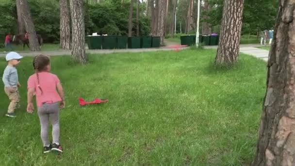 Tre glada förskola småbarn syskon barn vänner barn springa runt ha kul i sommar park leka på ängen hålla leksak flygplan sjösättning flyga upp i skyn. Barndom, vänskap, vila, natur — Stockvideo