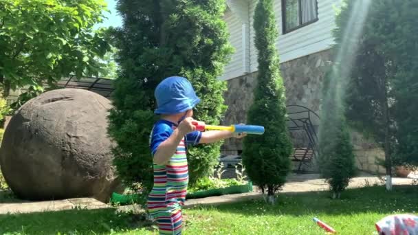 Cute Happy Kid Little Preschool Baby Girl und Boy Child Play haben Spaß mit Wasserpumppistole draußen. Sonnig heißer schöner Tag im Park. Kinder Hinterhof Garten Spiele. Sommer, Sport, Urlaub, Familie, Kindheit — Stockvideo