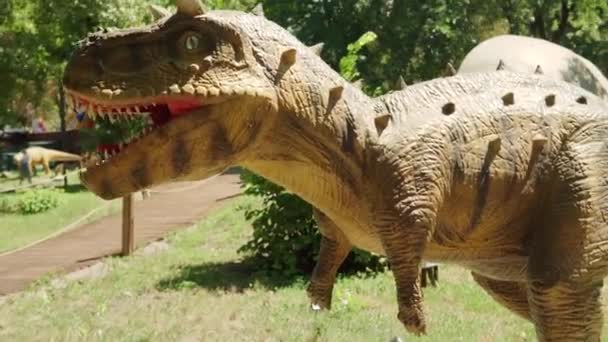 2021.08.12 - Kijów, Ukraina: Zmotoryzowany autentyczne wymiary Dinozaur Predator Carnotaurus makieta w parku rozrywki lasu. Wystawa Ruchomych Modeli Zwierząt z Jurajskiego okresu prehistorycznego w Dinoparku — Wideo stockowe