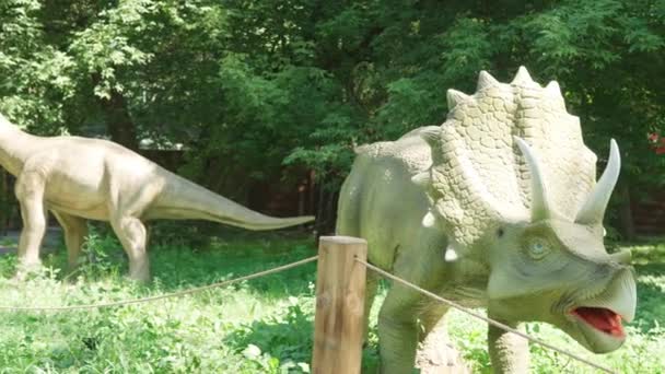 2021.08.12 - Kiev, Ukraine: Motorized Dinosaur Predator Triceratops and Brachiosaurus Mockup in Amusement Forest Park. Exhibition of Moving Models Animals from Jurassic Prehistoric Period in Dinopark — Stock Video