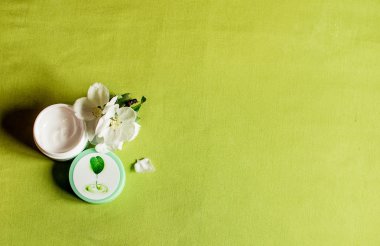 Yeşil bir arka plan üzerinde yüz kremi kavanoz