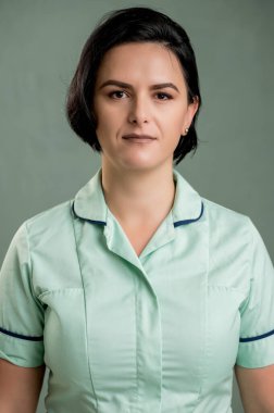 Yeşil gömlekli ve sarı eldivenli genç temizlikçi kadın, yeşil arka planda izole edilmiş.