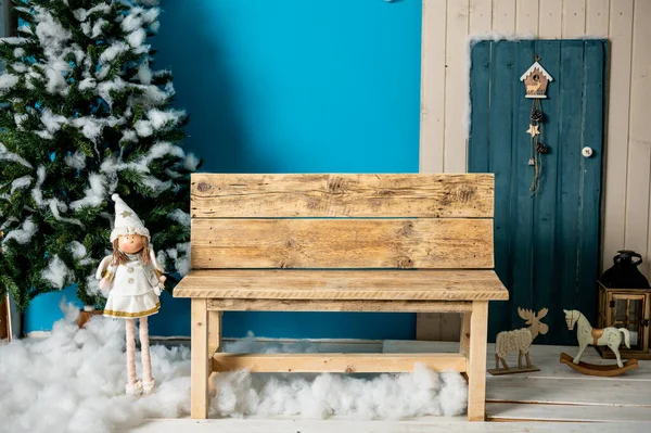 装饰圣诞工作室 带有蓝色门 木制长椅和滑雪板 假云彩和雪的房子 图库照片