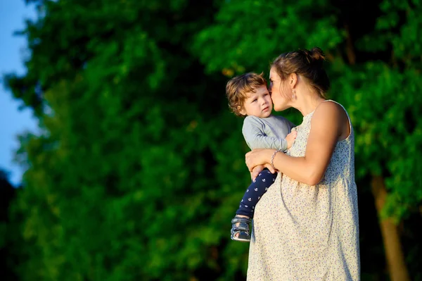 Fiatalok és a terhes anya átölelte a fiát a nyári park — Stock Fotó