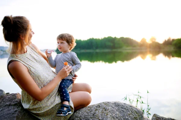 Młoda matka w ciąży spaceru z jej synka w lato park — Zdjęcie stockowe