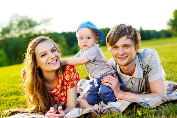 Smiling parents and their daughter lying in the grass — Stock Photo, Image