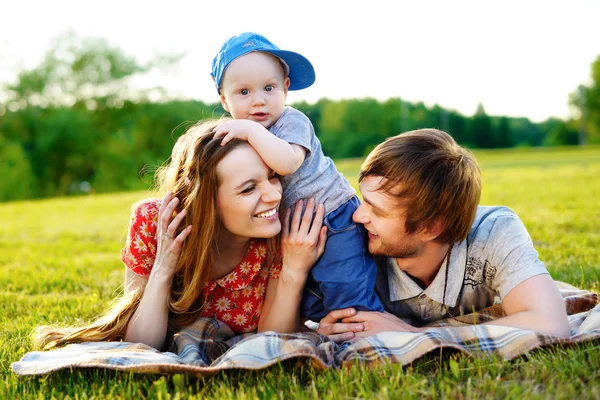 Happy and young family with a little son in summer park — Stock Photo, Image