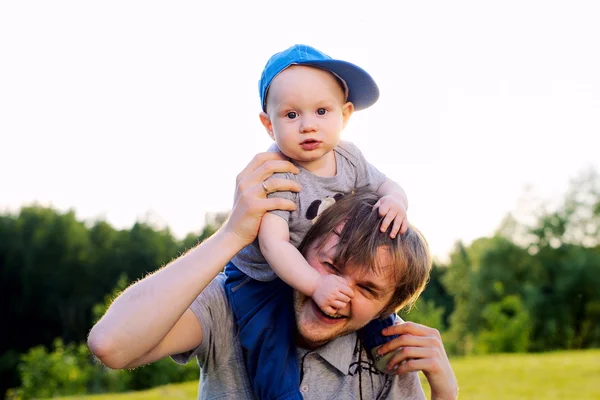 Joven padre feliz y descansando con su hijo en el parque de verano — Foto de Stock