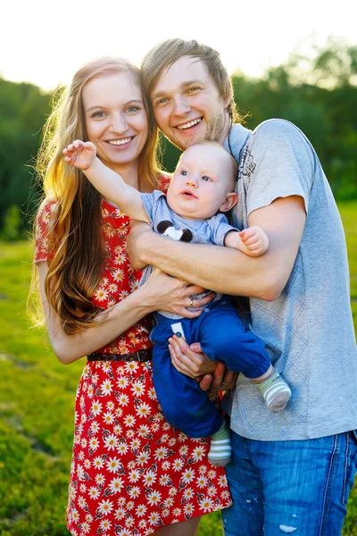 Happy parents holding her son arms on a picnic — Stock Photo, Image