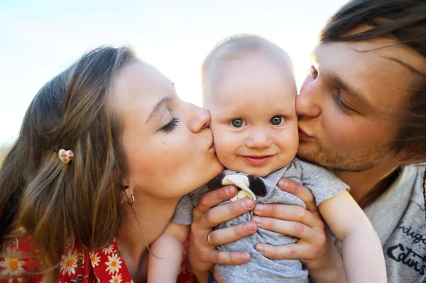 Mom and dad kiss on the cheek baby — Stock Photo, Image