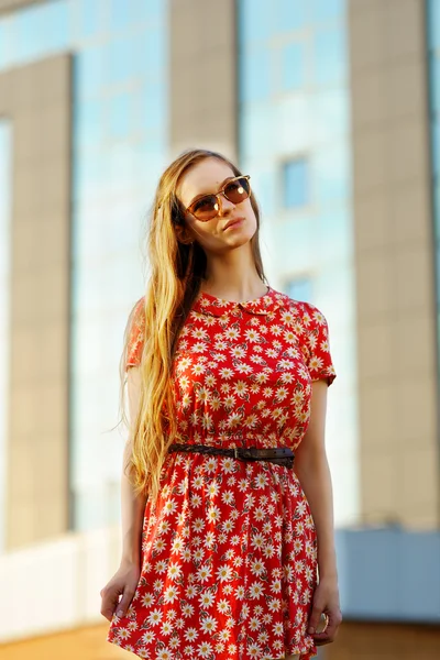Bella ragazza in un vestito rosso su uno sfondo di grattacielo costruire — Foto Stock