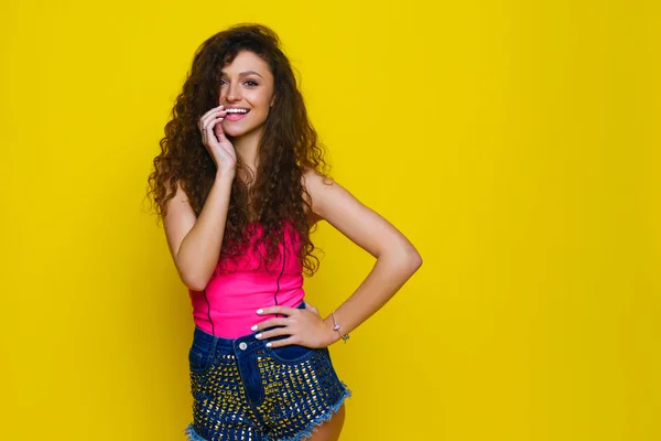 Junge und schöne lockige Mädchen in einem rosa Hemd und blauen Shorts o — Stockfoto