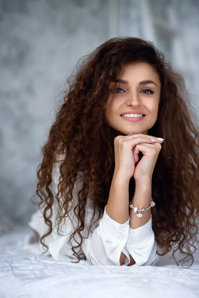 Retrato de una hermosa chica con el pelo rizado en la cama — Foto de Stock