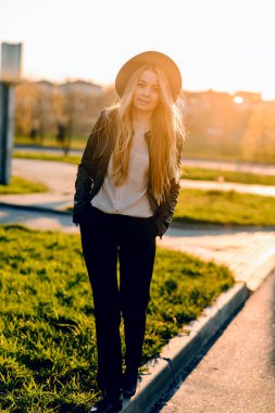 Gün batımında şehirde yürüyüş şapkalı güzel ve mutlu kız