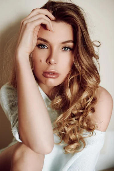 Beautiful sexy girl with curly hair sitting on the floor. Sexy look. Beautiful lips. Blue sweater — Stock Photo, Image