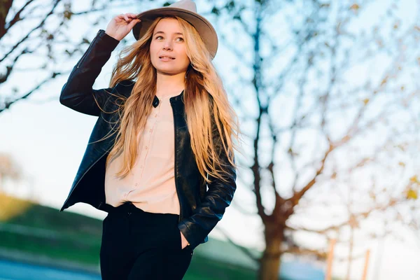 Bella ragazza con un cappello che cammina al tramonto in città — Foto Stock