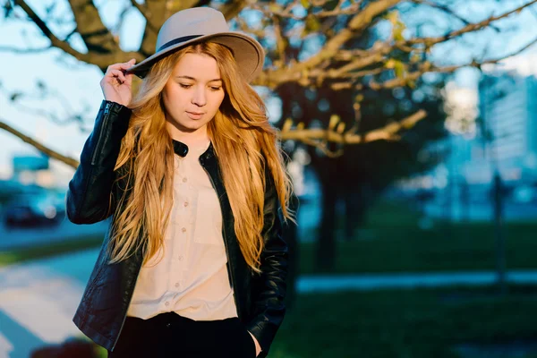 Gün batımında şehirde yürüyüş şapkalı güzel kız