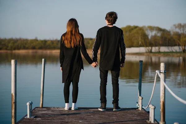 Happy couple holding hands and looking into the distance on a pier on a sunny summer day. love concept — Stock fotografie