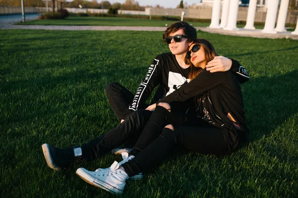 Pareja feliz abrazándose al atardecer en el césped en un día soleado de verano. Concepto de amor — Foto de Stock