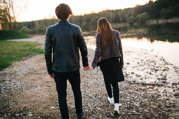 Glückliches Paar, das am Sommerabend am See spazieren geht und Händchen hält. Liebeskonzept — Stockfoto