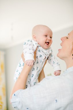 Genç anne, evdeki küçük oğlunun elini tutuyor. Annem mutlu. Çocuk mutlu ve gülüyor. Aile kavramı.