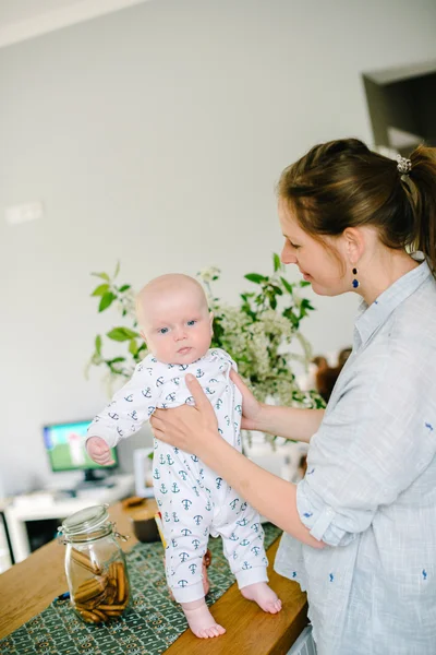 La jeune mère tient la main de son jeune fils à la maison. Maman heureuse. Enfant heureux et riant. Le concept de famille — Photo