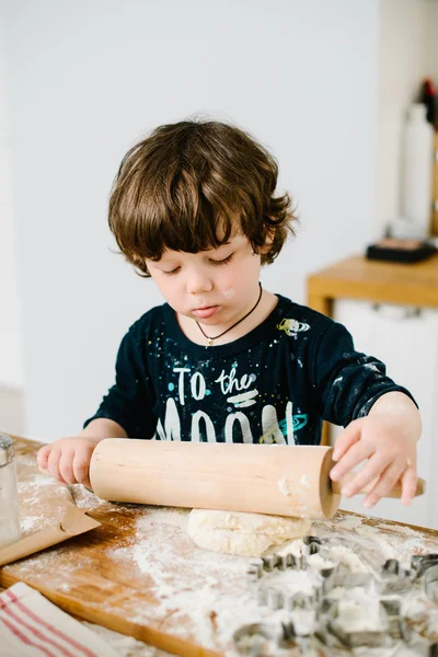Niño en la cocina ayudando a cocinar la masa para hornear — Foto de Stock