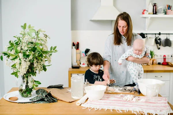 Young and happy mom with her children in the kitchen cook cookie