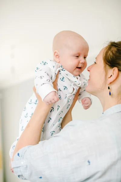 Genç anne, evdeki küçük oğlunun elini tutuyor. Annem mutlu. Çocuk mutlu ve gülüyor. Aile kavramı.