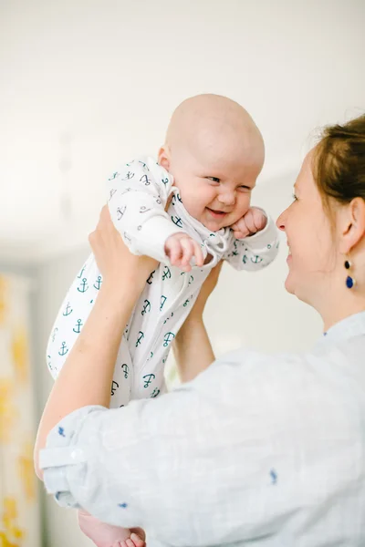 Ung mor håller i händerna på sin unge son hemma. Mamma lycklig. Barn glada och skrattar. Begreppet familj — Stockfoto