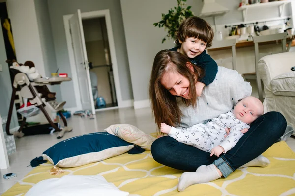 Mère jeune et heureuse jouant avec ses petits enfants sur le sol de la maison. Les enfants rient. Concept de famille — Photo