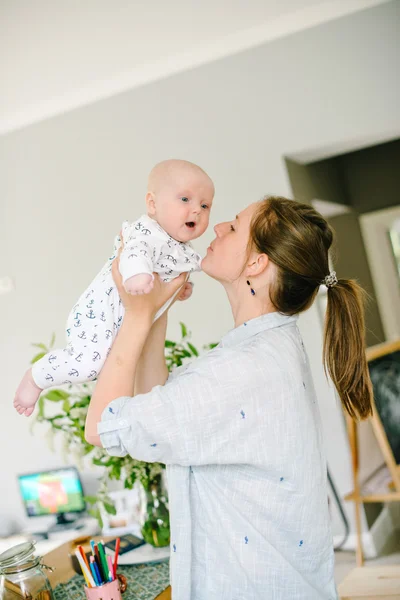 La jeune mère tient la main de son jeune fils à la maison. Maman heureuse. Enfant heureux et riant. Le concept de famille — Photo