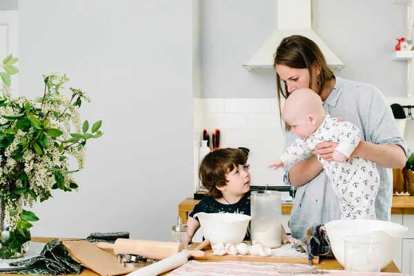 Jeune et heureuse maman avec ses enfants dans le biscuit de cuisine — Photo