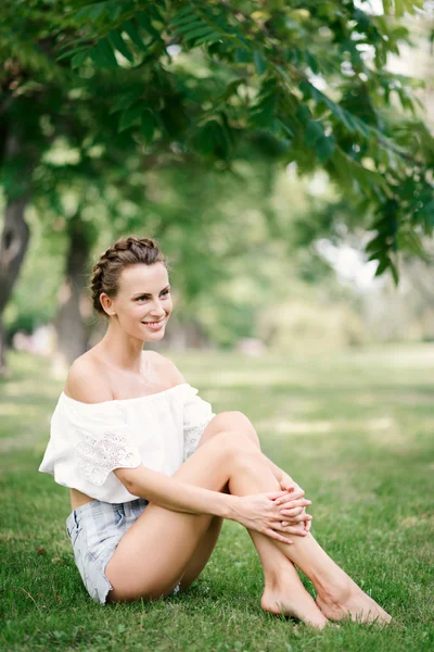 Hermosa chica sexy en pantalones cortos descansando en un parque en la hierba — Foto de Stock