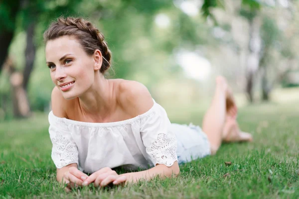 公園と残りの部分に草の上に横たわる若い美しいセクシーな女の子。美しい健康的な笑顔。派手な髪型。幸せな女の子 — ストック写真