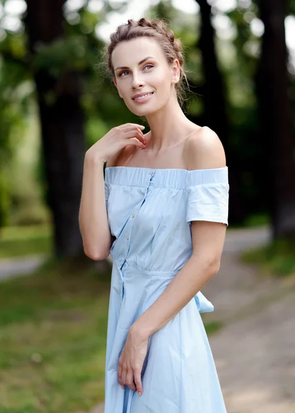 Szczupły, młoda dziewczyna w niebieskiej sukience w parku w lecie. Ładna fryzura. Pewien szczupły ciało. Zdrowy i piękny uśmiech — Zdjęcie stockowe