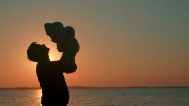 Babam gölün kenarında gün batımında çocukla oynuyor. 