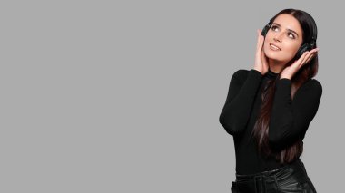 Kablosuz kulaklıklarla gülümseyen çekici kadın müzik dinler, gri arka planda izole bir şekilde.