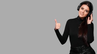 Kablosuz kulaklıklarla gülümseyen genç bir kadın baş parmak hareketini gösteriyor, bir kadın müzik dinliyor, izole edilmiş bir geçmişi var.