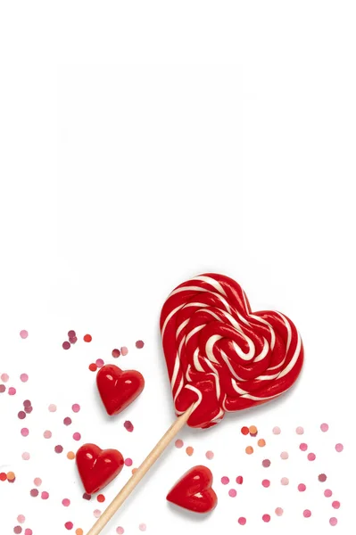 Червоні солодкі смачні льодяники та шоколадні цукерки у формі серця з конфетті. Шаблон Валентина. Ізольовані — стокове фото